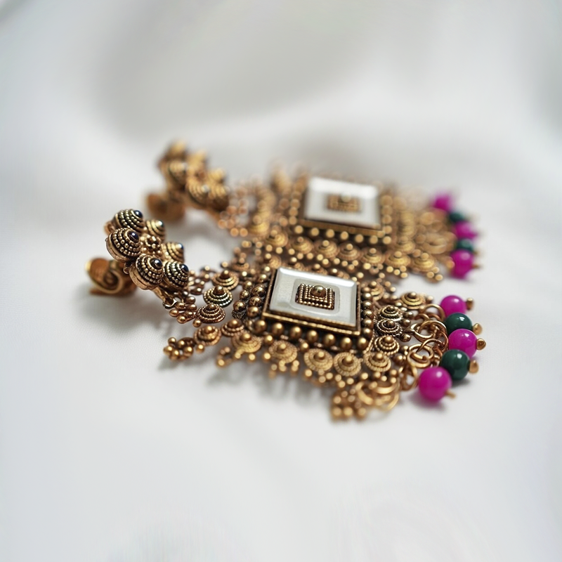 Antique Gold Toned Brass Jhumka Earrings With White Enamel Detail And Pink & Green Bead Drops